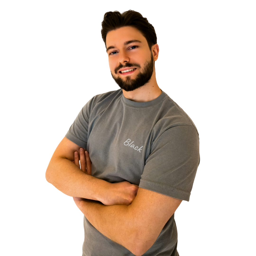 A smiling man wearing a Gray T-shirt with the word 'Black' embroidered in White on the left chest. This casual, premium cotton T-shirt is designed for a comfortable and modern fit, perfect for everyday wear and expressing a unique sense of style. The model stands confidently with arms crossed, showcasing the shirt's relaxed vibe.