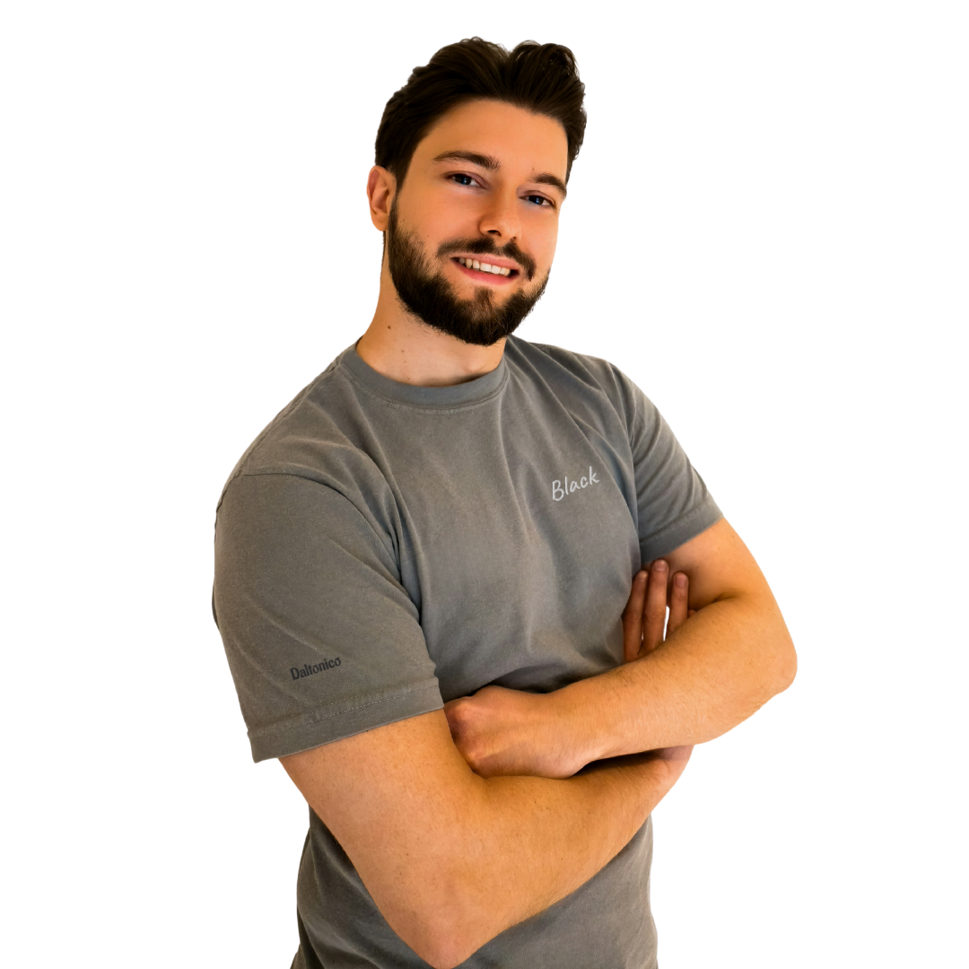 A smiling man wearing a Gray T-shirt featuring the word 'Black' embroidered in White on the left chest and the brand name 'Daltonico' subtly embroidered in Black on the left sleeve. This premium cotton T-shirt offers a modern, comfortable fit, perfect for casual wear and showcasing unique, stylish details. The model poses confidently with arms crossed.