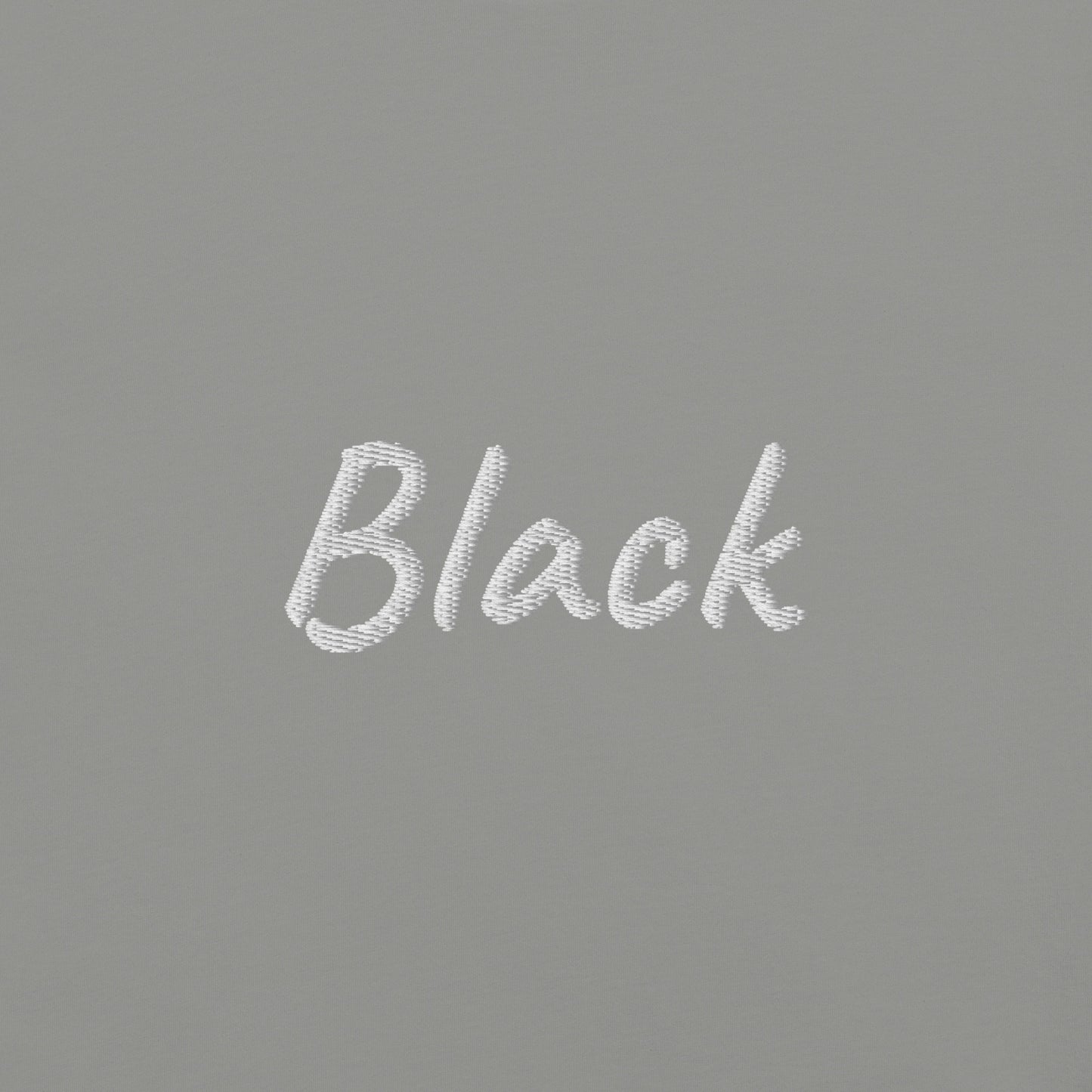 Close-up view of the word 'Black' embroidered in White on a Gray T-shirt. This detailed shot highlights the quality and precision of the embroidery, showcasing the unique design element that adds a bold touch to the T-shirt.