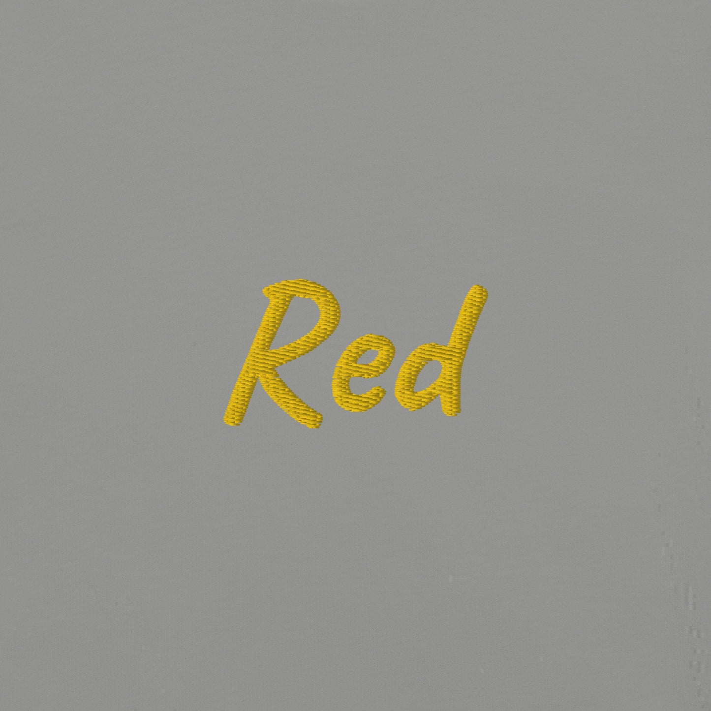 Close-up view of the word 'Red' embroidered in Yellow on a Gray T-shirt. This detailed shot highlights the quality and precision of the embroidery, showcasing the unique design element that adds a bold touch to the T-shirt.