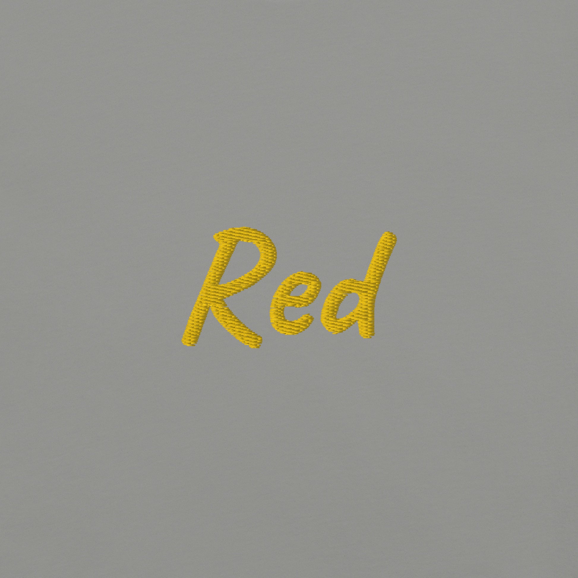 Close-up view of the word 'Red' embroidered in Yellow on a Gray T-shirt. This detailed shot highlights the quality and precision of the embroidery, showcasing the unique design element that adds a bold touch to the T-shirt.