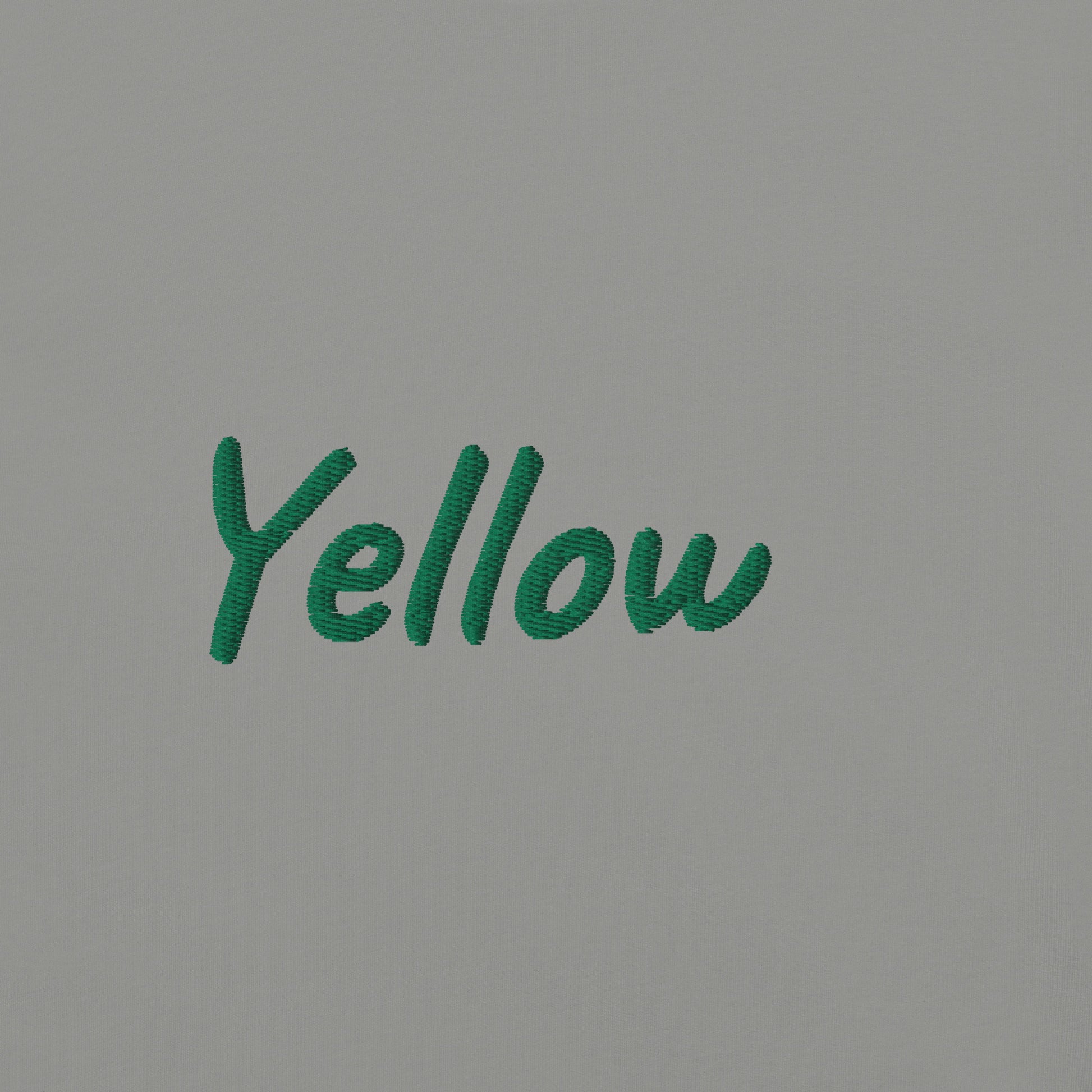 Close-up view of the word 'Yellow' embroidered in green on a gray T-shirt. This detailed shot highlights the quality and precision of the embroidery, showcasing the unique design element that adds a bold touch to the T-shirt.